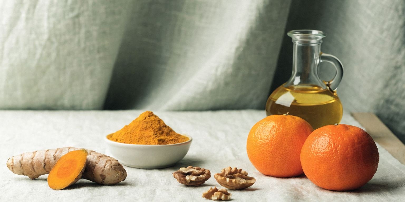 Bodegón con cúrcuma fresca y en polvo, naranjas, nueces y aceite dorado