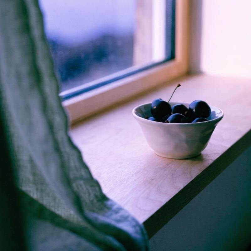 Cuenco de cerezas oscuras en una ventana al anochecer