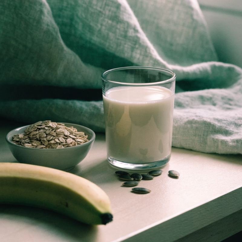 Leche templada, avena, plátano y pipas de calabaza sobre madera clara