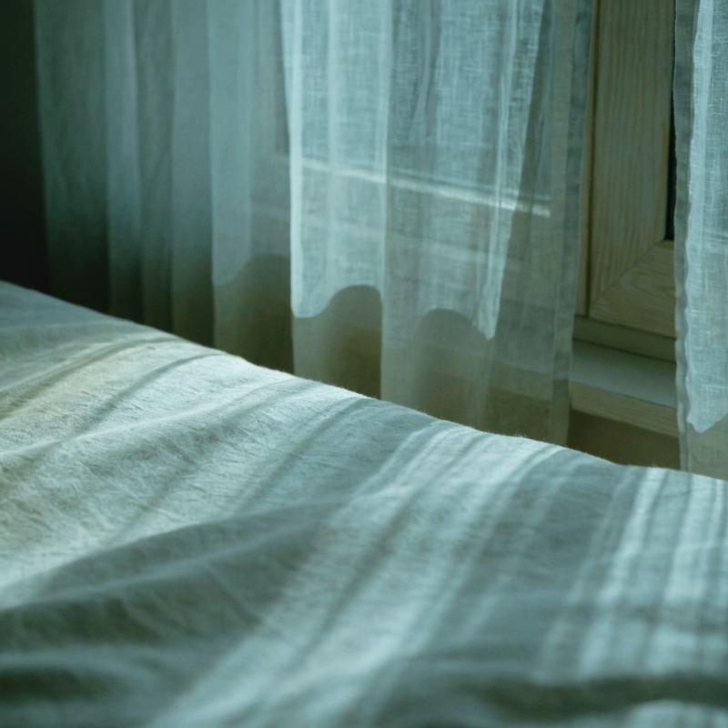 Luz de luna entrando por una ventana sobre ropa de cama de lino